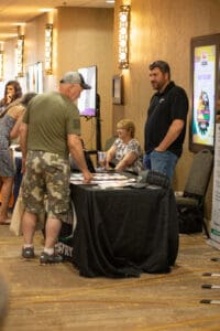 People interacting at an indoor event booth.