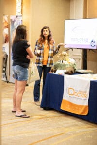 Two women talking at a booth display.