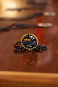 Logging badge on wooden table with necklace.
