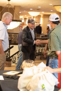 People shaking hands at indoor event.