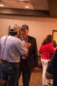 Two men talking at an indoor event.