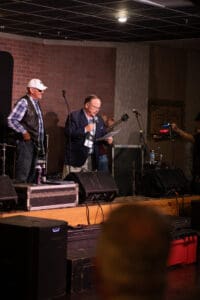 Men speaking on stage with microphones.