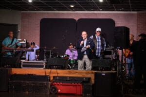 Band performing on stage with speaker present.