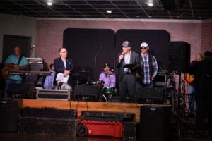 Band performing on stage with audience watching.