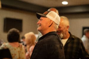 Smiling man in a cap at gathering.