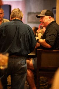 Two men talking in a dimly lit bar.