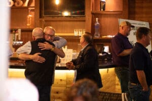 People hugging and socializing at a bar.