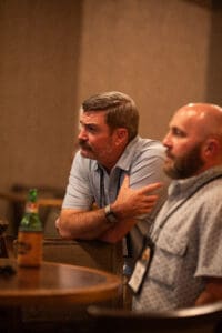 Two men sitting at a table, focused.