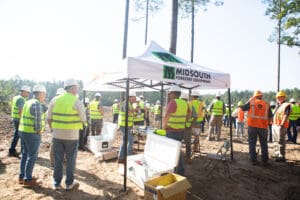 Workers gathering at forestry equipment tent.