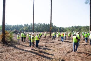 People in safety vests at deforested site.