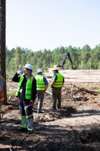 Construction workers in forest wearing safety vests.