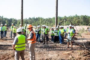 Construction workers gathered in forest clearing.