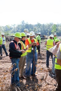 Workers wearing safety vests and helmets outdoors.
