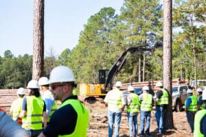 Workers and machinery in a forested area.