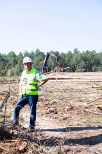 Worker in safety gear at logging site.