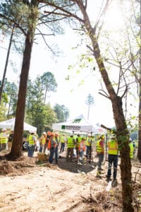 Workers gathered under tents in forest area.