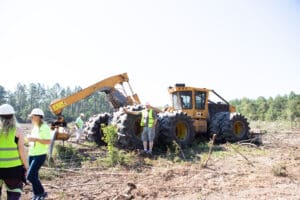 People working near large construction vehicle outdoors.