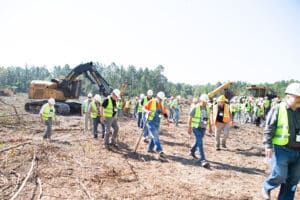 Workers touring cleared construction site with excavators