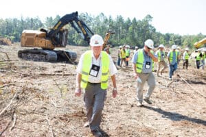 Construction crew inspecting cleared site with excavator