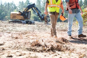 Construction workers walking near an excavator.