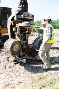 Workers inspecting heavy machinery at construction site.