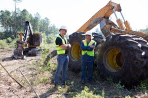 Two workers talking near construction machinery.