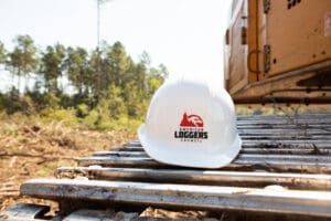 Hard hat on machinery in forest setting.