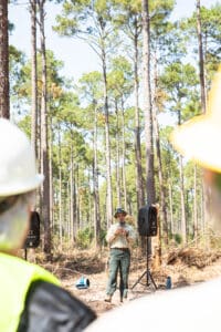 Forestry ranger addressing workers in pine forest