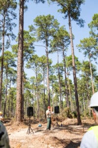 Person speaking in a forest setting.