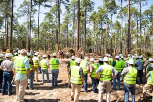 Forest workers gathering in safety vests outdoors.