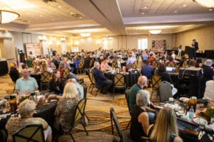 Crowded banquet hall with people seated at tables.