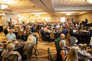 Conference attendees seated at round tables.
