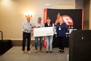 Four people holding a large check on stage.