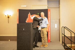 Two men embracing on stage at conference