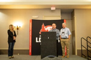 Three presenters on stage at conference podium