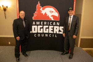 Two men standing by American Loggers Council banner.