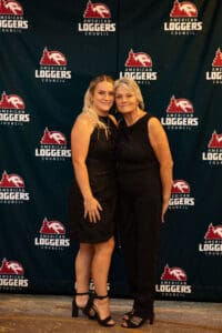 Two women posing at an event backdrop.