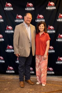Man and woman posing at event backdrop.