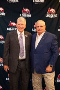 Two men in suits at loggers backdrop