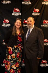 Man and woman posing at American Loggers backdrop