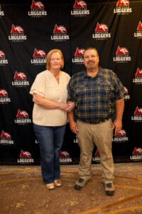 Couple posing at Loggers Council event backdrop.