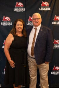 Two people posing at American Loggers Council backdrop