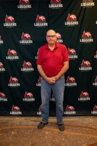 Man standing before Loggers Council backdrop.