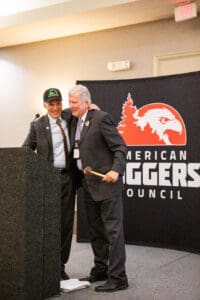 Two men hugging at podium, Loggers Council banner