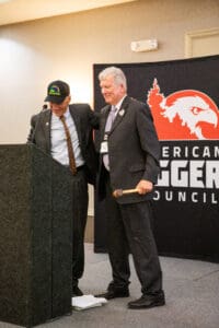 Two men at podium with banner behind.