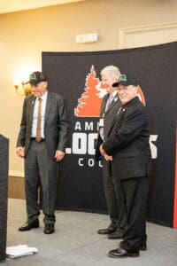 Three men in suits and hats smiling.