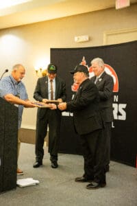 Men exchanging documents at an awards event.