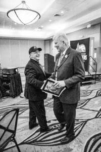 Two men exchanging books at event.