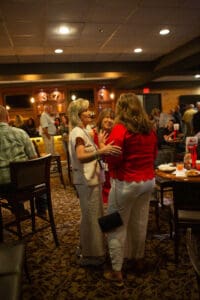 Three women chatting at a lively gathering.