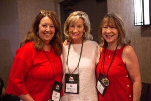 Three women smiling at a conference.